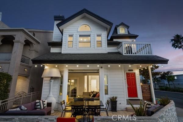 back house at dusk featuring a balcony