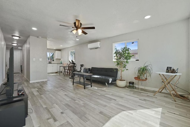 living room with light wood-type flooring, ceiling fan, and a wall mounted AC