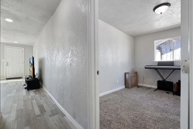 hallway featuring light carpet and a textured ceiling