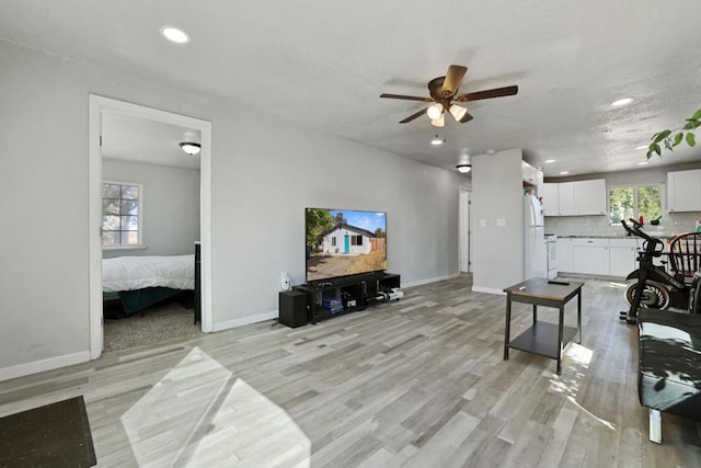 living room with ceiling fan, light hardwood / wood-style floors, and a wealth of natural light