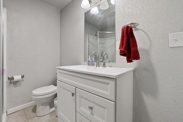 bathroom featuring tile patterned flooring, walk in shower, vanity, and toilet