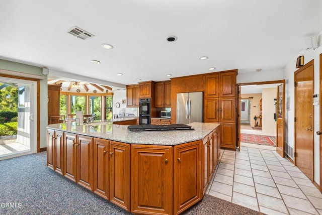 kitchen featuring a center island, light stone counters, light tile patterned floors, and appliances with stainless steel finishes