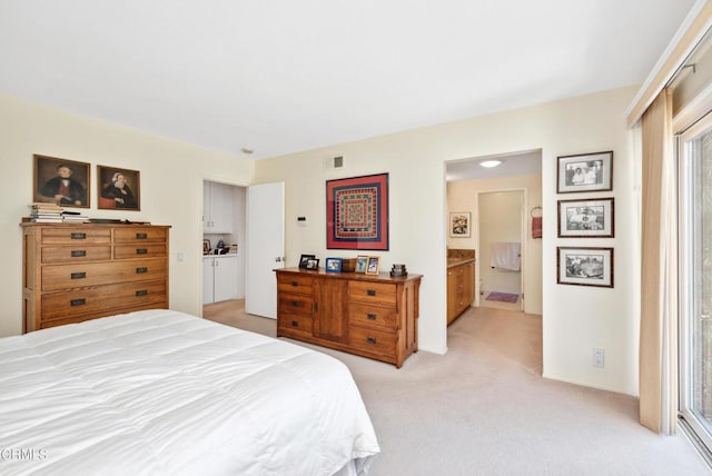 bedroom featuring connected bathroom and light carpet