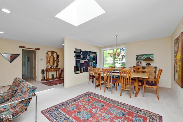 carpeted dining area featuring a skylight and an inviting chandelier