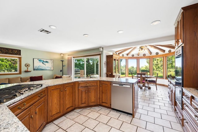 kitchen featuring ceiling fan, light stone counters, kitchen peninsula, and appliances with stainless steel finishes