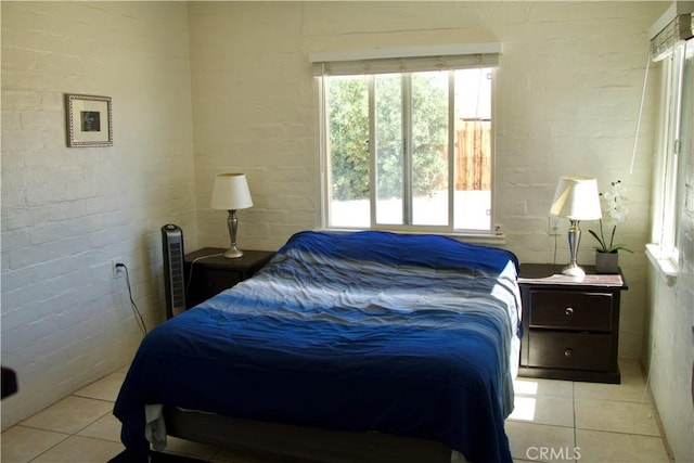 bedroom with light tile patterned floors and brick wall