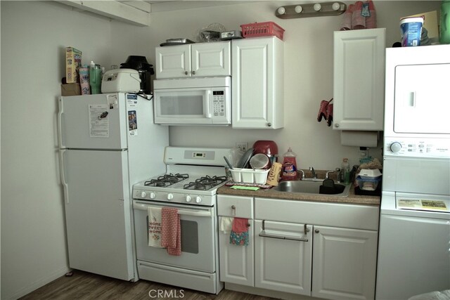 kitchen featuring white cabinets, sink, white appliances, stacked washing maching and dryer, and dark hardwood / wood-style floors