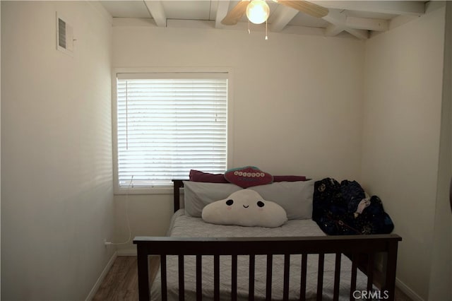 bedroom with ceiling fan, beamed ceiling, and hardwood / wood-style flooring