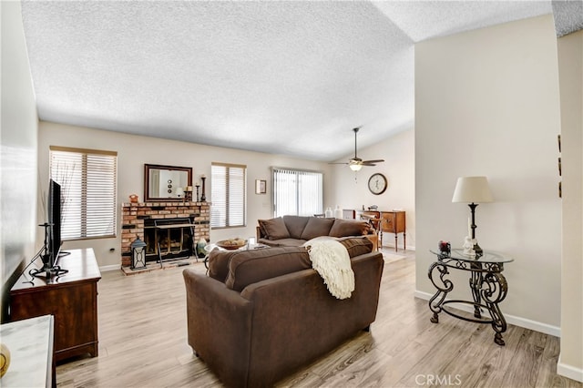 living room with light wood-type flooring, lofted ceiling, a fireplace, and ceiling fan