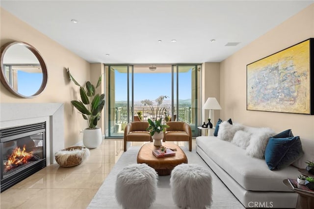 living area with expansive windows and a glass covered fireplace