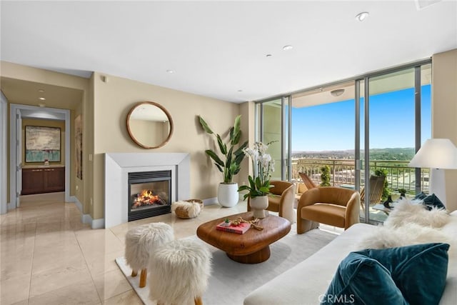 living room with expansive windows, a glass covered fireplace, baseboards, and light tile patterned floors