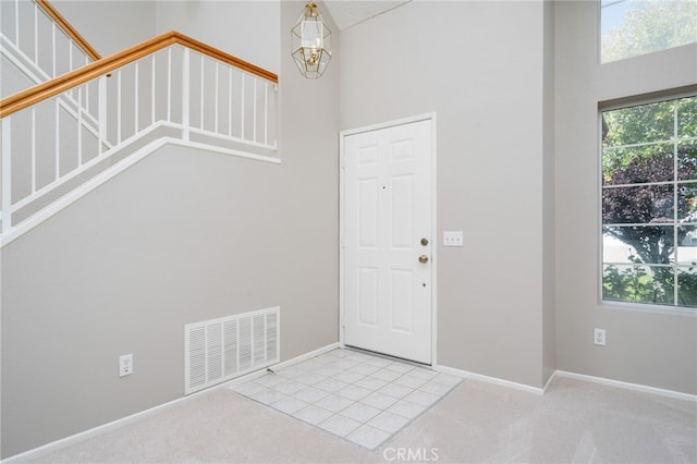 carpeted foyer entrance featuring a notable chandelier