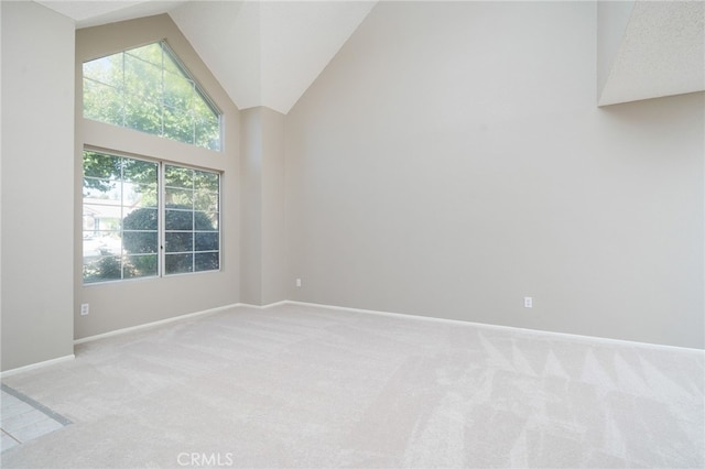 carpeted empty room featuring high vaulted ceiling and plenty of natural light