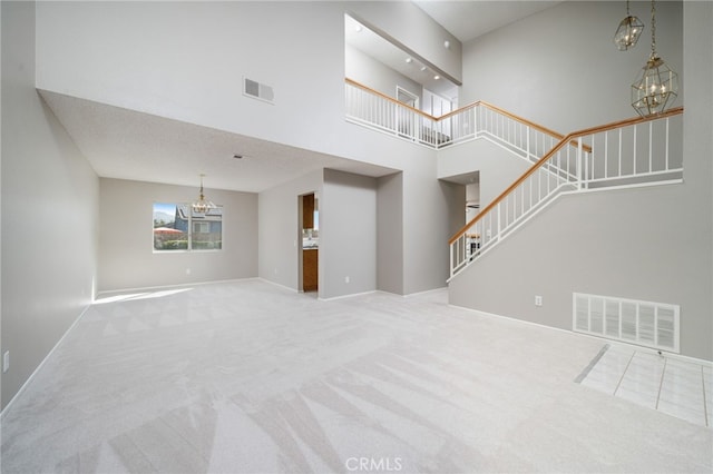 unfurnished living room with light colored carpet, a chandelier, and a high ceiling