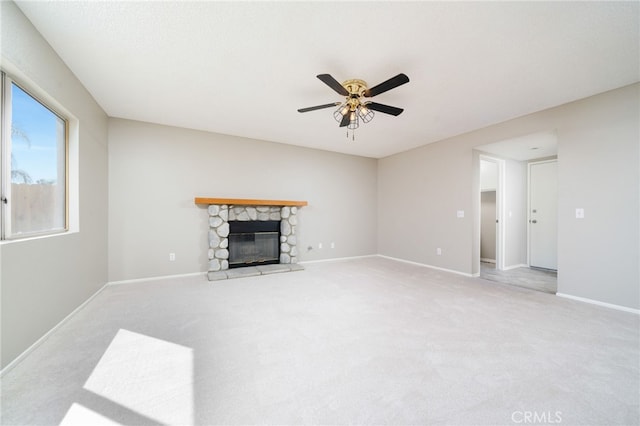 living room featuring ceiling fan, light colored carpet, and a stone fireplace