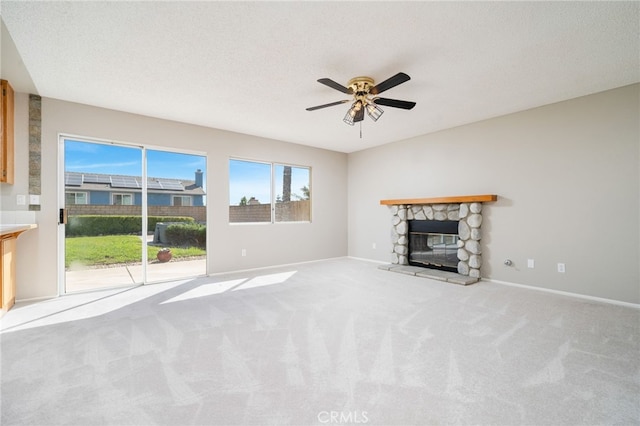 unfurnished living room featuring ceiling fan, carpet floors, a fireplace, and a textured ceiling