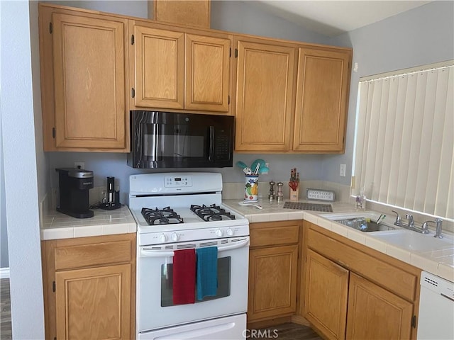 kitchen featuring tile countertops, white appliances, sink, and vaulted ceiling