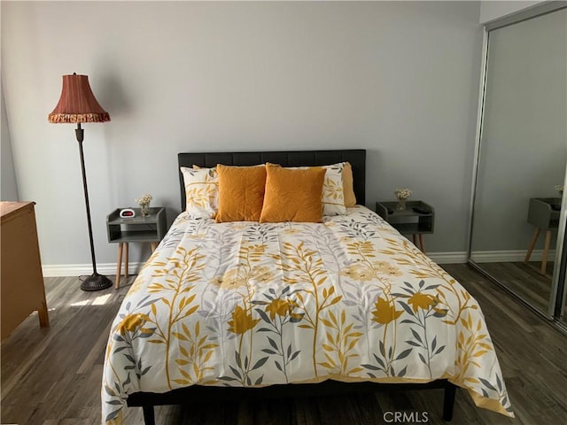 bedroom with dark hardwood / wood-style flooring and a closet