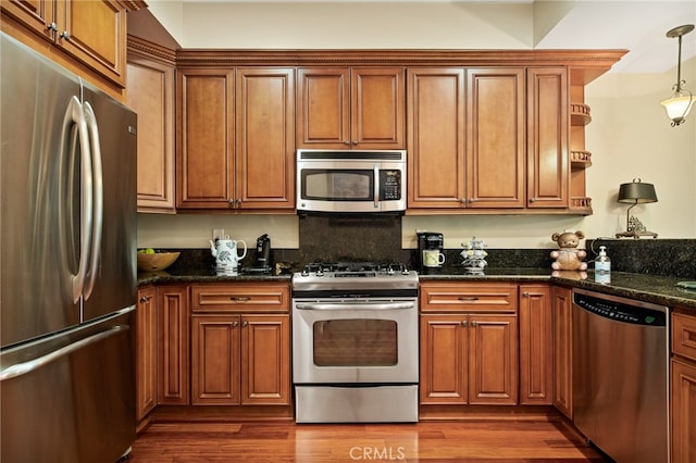 kitchen with dark stone counters, appliances with stainless steel finishes, hanging light fixtures, and dark hardwood / wood-style flooring