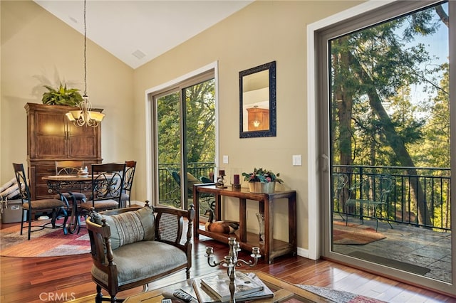 living area with lofted ceiling, hardwood / wood-style floors, and a chandelier