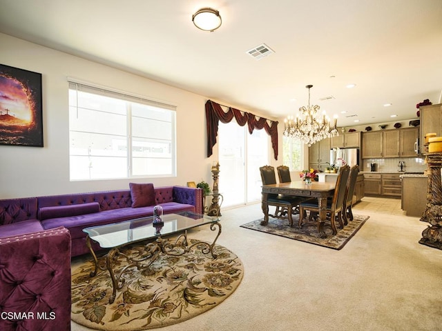 carpeted living room with an inviting chandelier and a healthy amount of sunlight