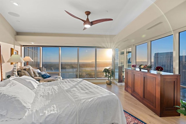 bedroom featuring ceiling fan, multiple windows, and light hardwood / wood-style flooring