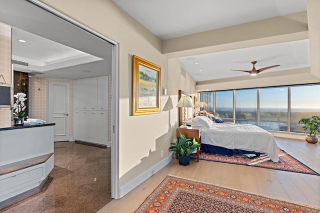 bedroom featuring a raised ceiling, hardwood / wood-style flooring, and ceiling fan