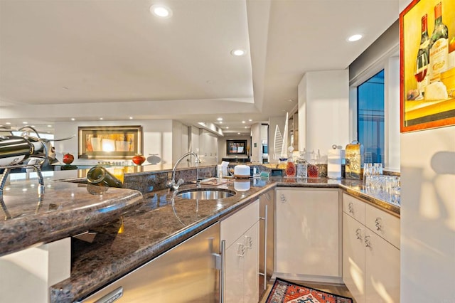 kitchen featuring sink, white cabinets, and dark stone counters