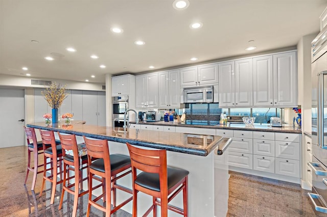 kitchen with a spacious island, stainless steel appliances, a kitchen bar, and white cabinets