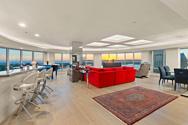 living room featuring a water view, coffered ceiling, and light hardwood / wood-style flooring