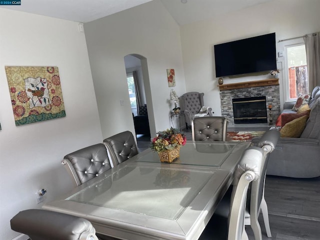 dining area with hardwood / wood-style flooring, plenty of natural light, and a stone fireplace