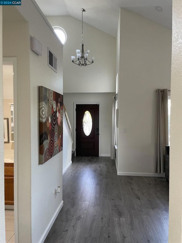 foyer entrance with dark hardwood / wood-style floors, high vaulted ceiling, and a chandelier