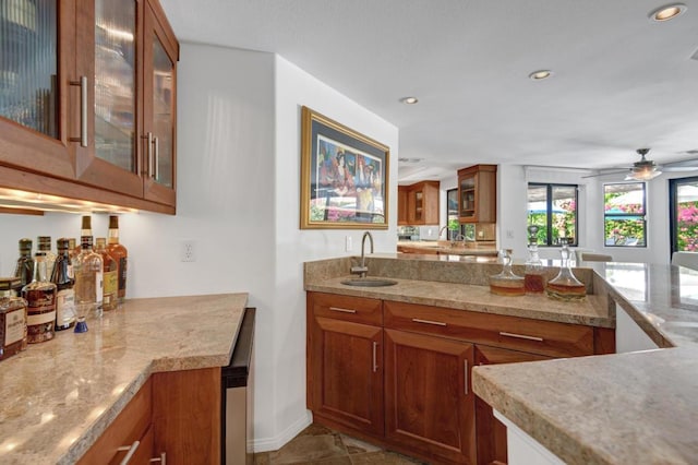 kitchen with light stone countertops, ceiling fan, and sink