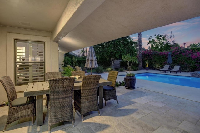 pool at dusk featuring a patio