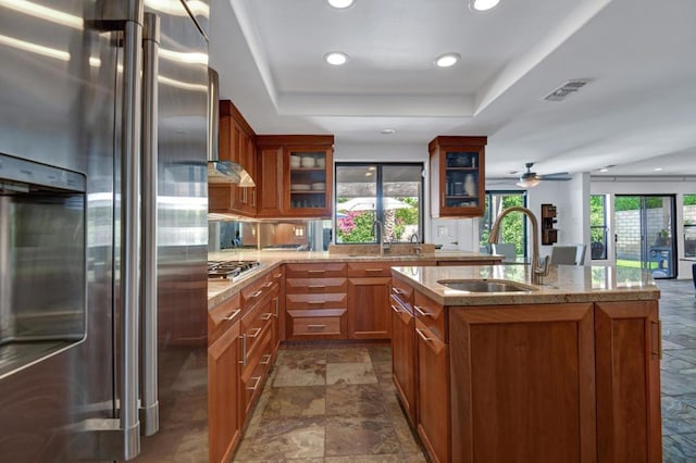 kitchen featuring sink, a kitchen island with sink, a tray ceiling, and high end fridge