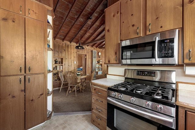 kitchen with wood ceiling, lofted ceiling with beams, wooden walls, and stainless steel appliances