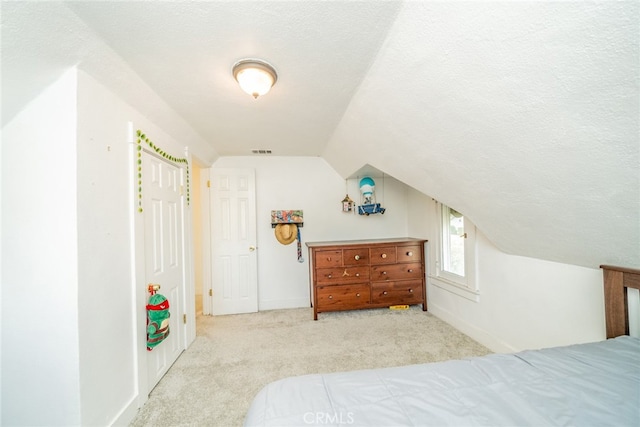 carpeted bedroom featuring vaulted ceiling and a textured ceiling