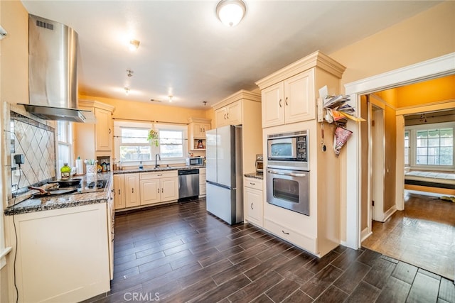 kitchen featuring dark stone countertops, appliances with stainless steel finishes, dark hardwood / wood-style flooring, and range hood