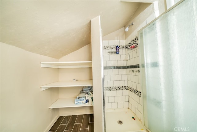 bathroom featuring vaulted ceiling and tiled shower