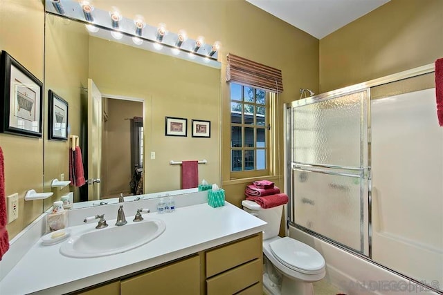 full bathroom with enclosed tub / shower combo, vanity, and toilet