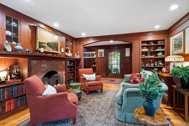 living room with a fireplace, wood walls, light hardwood / wood-style floors, and built in features