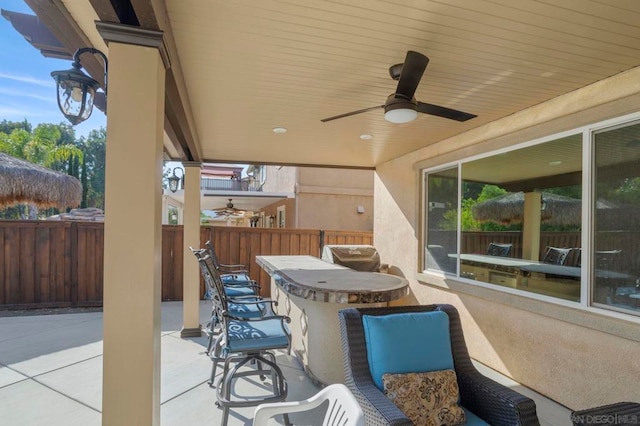 view of patio with area for grilling, ceiling fan, and exterior bar