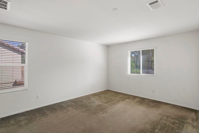 unfurnished room featuring a healthy amount of sunlight and dark carpet