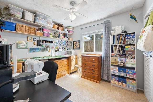 home office featuring light carpet, ceiling fan, and a textured ceiling