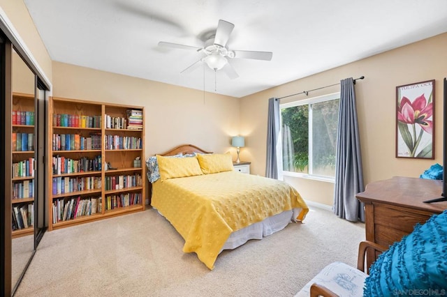 carpeted bedroom featuring ceiling fan and a closet