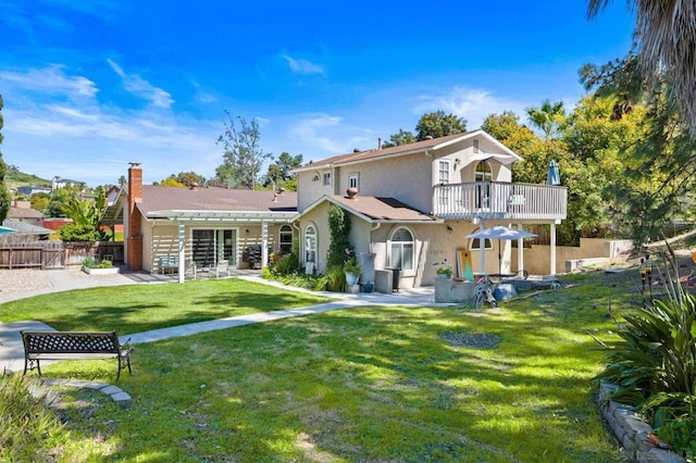 rear view of house with a lawn and a balcony