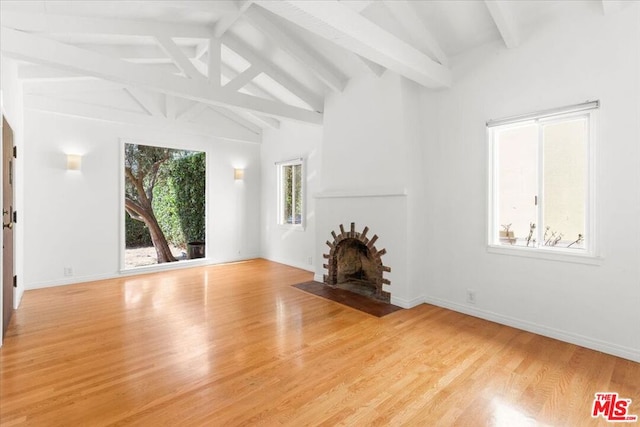 unfurnished living room featuring light wood-type flooring and lofted ceiling with beams