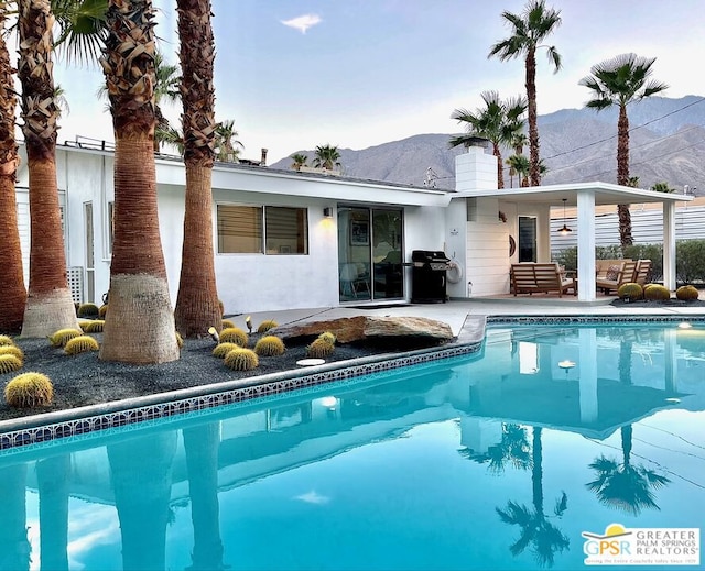 view of pool with a grill, a mountain view, ceiling fan, and a patio