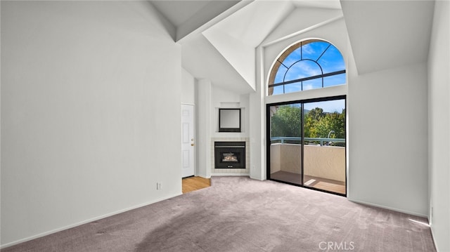 unfurnished living room with high vaulted ceiling and light colored carpet