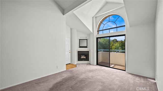 unfurnished living room with high vaulted ceiling and light colored carpet